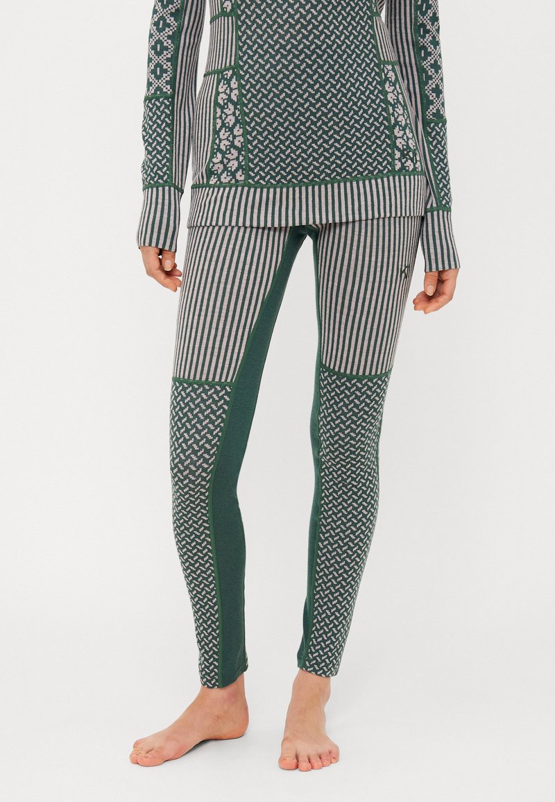 Conjunto deportivo en verde y gris con estampados que incluye una camiseta de manga larga y leggings ajustados con diseños a rayas y geométricos. Textura de tela suave.