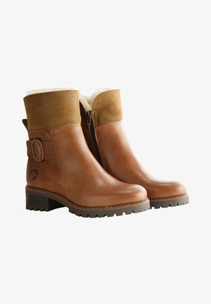 Bottes basses en cuir marron avec un revers en daim, un détail à boucle et une fermeture éclair latérale. La semelle est texturée pour une meilleure adhérence. Doublées en matériau doux.