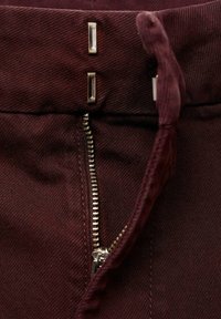 Pantaloni bordeaux con zip in metallo, due dettagli con bottoni argentati e tessuto testurizzato per una maggiore resistenza.