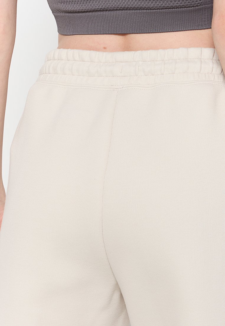 Pantalones de chándal beige con una textura suave, cinturilla elástica y diseño de pierna recta. Estilo minimalista, adecuado para uso casual.