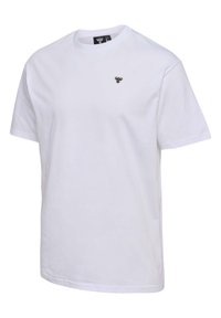 Hvid bomulds t-shirt med korte ærmer, rund hals, og et lille sort og guld logo på det øverste venstre bryst. Glat tekstur, normal pasform.