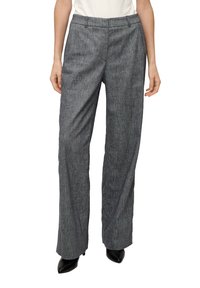 Pantalons larges gris avec un motif texturé, featuring des passants de ceinture, un devant plat et une coupe décontractée, associés à des talons aiguilles noirs.