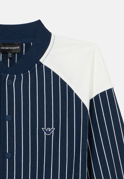 Μπλε σκούρο και λευκό πουκάμισο με μακριά μανίκια, κάθετες λευκές λεπτές ρίγες, κουμπιά τύπου σναπ σε μπλε σκούρο χρώμα, ριμπ λαιμόκοψη και κεντημένο λογότυπο Emporio Armani στο στήθος.