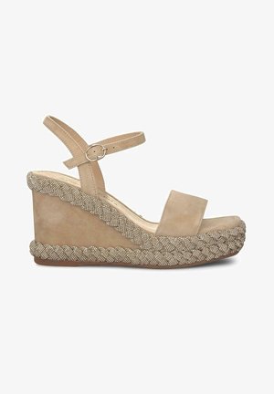 Beige suède wedge sandaal met een brede teengreep, enkelband en decoratieve geweven details langs de basis van de wedge.