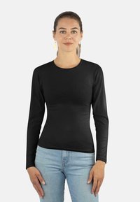 Schwarzes Langarmoberteil aus glattem Stoff mit rundem Halsausschnitt. Getragen mit hellblauen Jeans. Schlichtes, eng anliegendes Design ohne Muster.