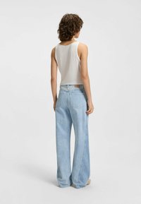 Jasnoszary prążkowany top na ramiączkach zestawiony z jasnoniebieskimi spodniami typu wide-leg. Spodnie mają wysoką talię i subtelne tylne kieszenie. Gładki, miękki materiał.