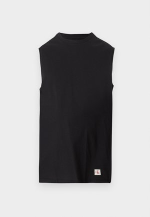 Haut noir sans manches à col rond avec un petit patch logo Calvin Klein blanc près de l'ourlet inférieur sur un fond clair uni.
