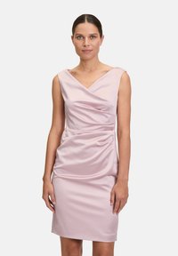 Abito in satin rosa tenue con silhouette aderente, scollatura a V e dettagli arricciati in vita, che si estende fino a metà coscia.