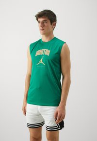 Green sleeveless shirt with "BOSTON" graphic in gold; paired with white mesh shorts featuring black stripes and dotted texture.