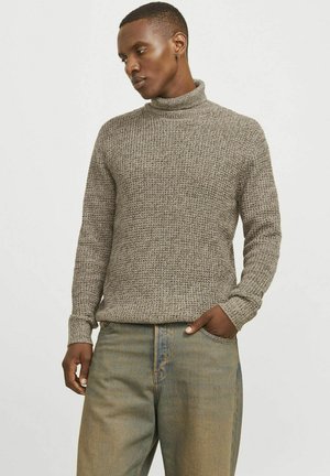 Strick-Turtleneck-Pullover in erdigem Grau mit einem strukturierten Muster und gerippten Bündchen. Kombiniert mit locker sitzenden, hellblauen Jeans.
