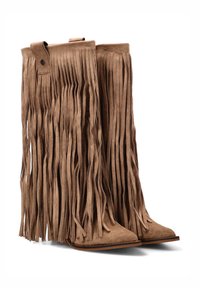 Botas de ante marrón hasta el tobillo con detallados flecos largos, punta afilada y suela plana. La textura notable y el diseño en capas añaden interés visual.