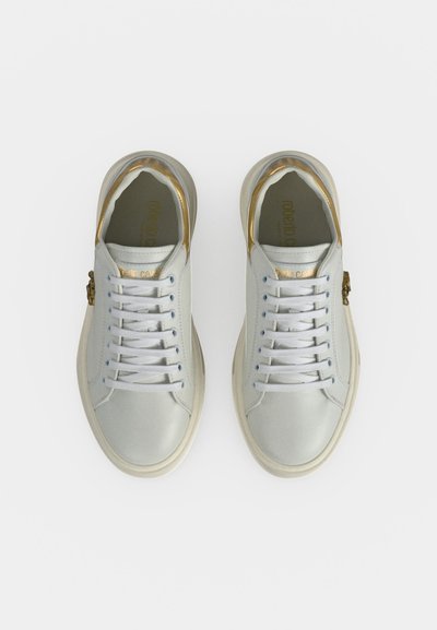 Ζευγάρι λευκά sneakers χαμηλού τύπου με χρυσές λεπτομέρειες στη φτέρνα και τα κορδόνια, από πάνω σε λευκό φόντο.