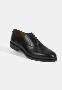 Chaussure habillée en cuir noir avec un bout rond, des lacets et des détails de couture subtils. Elle possède un petit talon et une texture lisse.