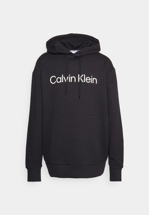 Melns kapucis krekls, izgatavots no mīksta auduma, ar priekšējo kabatu, aukliņu kapuci un "Calvin Klein" logo baltā krāsā uz krūtīm.