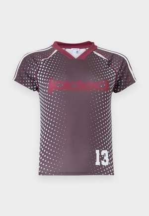 Kortermet sportstrøye i mørk lilla med hvitt prikkemønster, burgunder krage og hvit nummer 13 på nedre fremre høyre side.