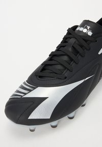 Paire de chaussures de football noires en cuir, avec un design accentué en argent, une surface texturée et un système de laçage traditionnel avec des crampons coniques.