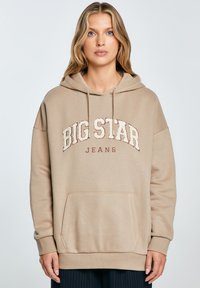 Béžová oversized mikina s přední kapsou, kapucí na šňůrky a nápisem "BIG STAR JEANS" vytištěným v kontrastní bílé a vínové barvě.