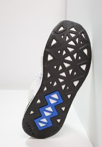 Musta kumi pohja, jossa on teksturoitu pinta, kolmiomaisia aukkoja ja sininen geometristen muotojen koristelu, pääasiassa valkoinen tausta.