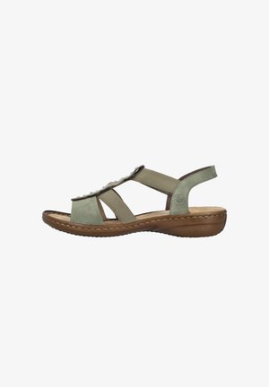 Sandale vert clair à bout ouvert avec brides élastiques, ornements cloutés, semelle marron rembourrée et talon compensé bas.