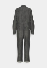 Mono de mezclilla gris oscuro con mangas largas, puños con botones y cintura elástica. Cuenta con dos bolsillos traseros y puños enrollados en los tobillos.