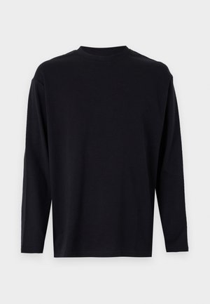 Juodas ilgomis rankovėmis marškinėliai iš lygaus audinio. Turi apvalią iškirptę, laisvą kirpimą ir jokių matomų raštų ar puošmenų.