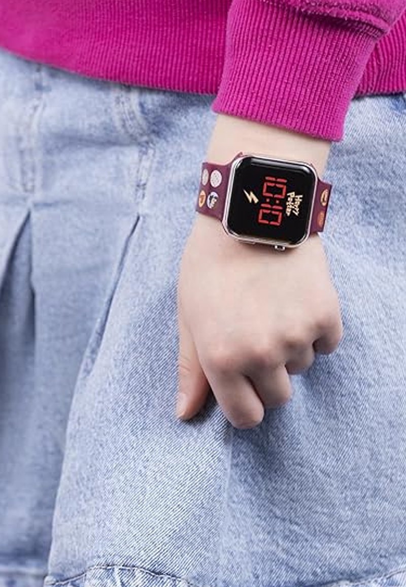 Montre numérique avec un cadran carré noir, affichage numérique rouge et un bracelet bordeaux arborant divers designs et motifs colorés.