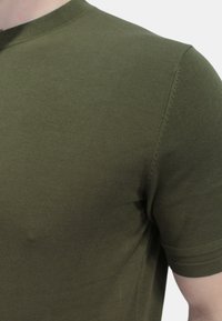 T-shirt a maniche corte verde oliva realizzato in tessuto a coste, con scollatura a girocollo e cuciture piatte lungo le spalle.