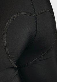 Schwarze, enganliegende Sportleggings aus strukturiertem Stoff mit flachen Nähten und konturiertem Design. Es sind keine sichtbaren Markenkennzeichen vorhanden.