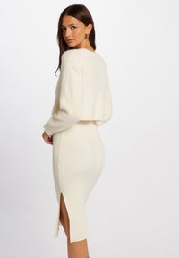 Crème-kleurige twee-delige outfit bestaande uit een zachte, pluizige cropped trui en een geribde midi-jurk met zijsplits.