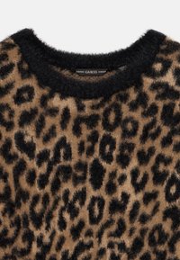 Myk og lodden genser med svart og brunt leopardmønster og svart rund hals.
