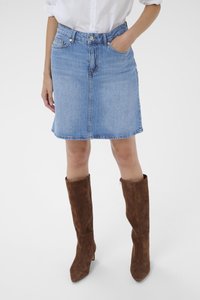 Jeans krilo, svetlo modro, do kolen, s klasičnim krojem, sprednjimi žepi in rahlo ukrivljenim robom. Ujemite s rjavimi semiš škornji do kolen.