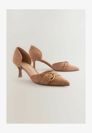 Nude zamszowe szpilki z ostrym noskiem, dekoracyjnym paskiem z złotą okrągłą klamrą i smukłą szpilką.