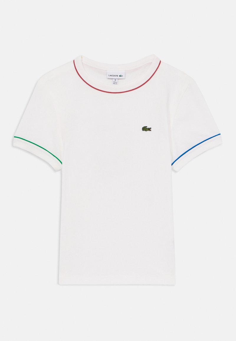 Balta T-kreklu ar īsām piedurknēm, akcentēts ar sarkano, zaļo un zilo apdari ap apkakli un piedurknēm. Uz tā ir neliels zaļš logotips.