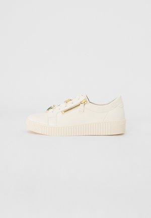 Witte sneaker met een gladleren bovenkant, ronde neus, gouden ritsaccent aan de zijkant en een gestructureerde rubberen zool.
