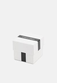 Caja de regalo blanca con una banda horizontal negra que presenta el logotipo de Calvin Klein. Forma cuadrada con una textura suave y un diseño con tapa extraíble.