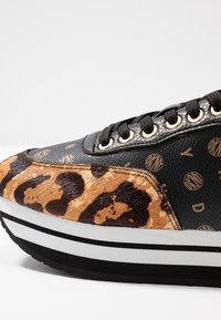 Baskets noires et imprimé léopard avec une surface texturée, œillets dorés, semelle en caoutchouc blanche et noire, et accents de logo sur le dessus.