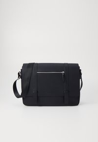 Sacoche noire en matériau lisse, dotée d'une poche avant zippée, d'une bandoulière réglable et d'un design minimaliste sans logo visible.
