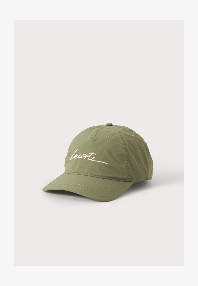 Casquette de baseball vert olive avec une visière incurvée et un logo blanc en écriture cursive à l'avant, affichée sur un fond clair uni.