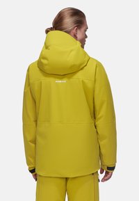 Gelbe wasserdichte Jacke mit Kapuze, verfügt über eine glatte Textur, elastische Bündchen und ein sichtbares Logo auf dem Rücken. Maßgeschneiderter Entwurf für den Einsatz im Freien.