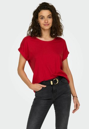 T-shirt rouge à manches courtes avec une coupe décontractée et un col rond, associé à un jean noir ajusté et une ceinture noire avec une boucle dorée.