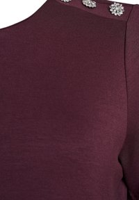 Burgundské oblečení se hladkým, elastickým materiálem, s dekorativními krystalovými květinovými akcenty na rameni.
