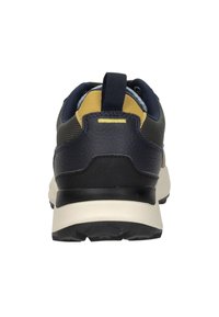 Marineblauwe en zwarte sneaker met een gestructureerde bovenkant, gele accenten en een trekhaak; heeft een gevoerde witte zool en een patroon op de loopzijde.