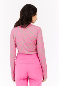 Camiseta de manga larga en rosa y beige con un patrón de rayas de cebra, combinada con pantalones ajustados rosa brillante. Textura suave, diseño atlético.