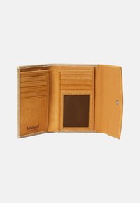 Portafoglio in pelle tan con molteplici scomparti per carte, una finestra per l'ID in rete e cuciture tonali. Presenta un interno testurizzato e un logo impresso.