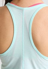 Débardeur de sport bleu clair avec un design dos nageur, une texture douce et des accents roses contrastants près de l'encolure et des emmanchures.