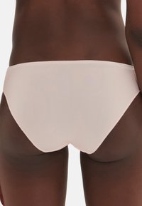 Rosa Unterwäsche mit einer glatten, matten Oberfläche, im Low-Rise-Design und subtilen gewellten Kanten, die eine nahtlose und minimalistische Form betont.