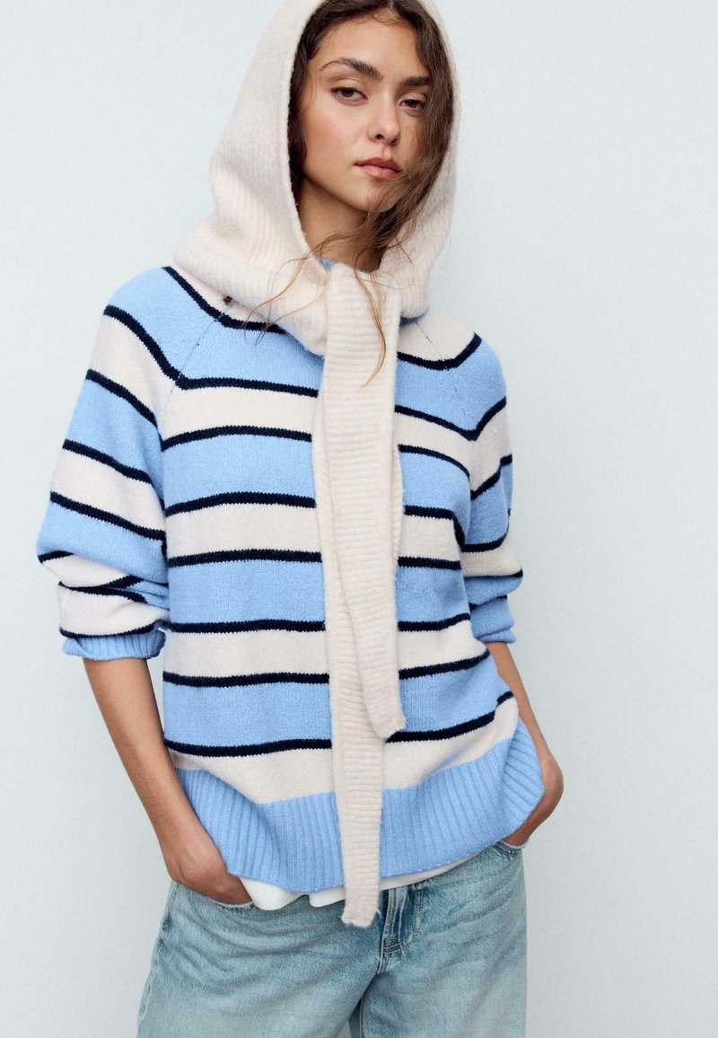 Maglione a righe in azzurro chiaro, crema e blu navy. Presenta un cappuccio spesso simile a una sciarpa e polsini a coste, con una vestibilità comoda e una tasca frontale.