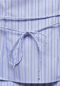 Tissu bleu clair à rayures blanches verticales. Dispose d'une ceinture nouée avec de fines cordelettes à la taille. Texture douce et finition lisse.