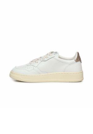 Baskets basses en cuir blanc avec semelle crème, bout perforé, lacets beiges et languette métallique bronze au talon, vues de côté droit.