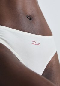 Valge puuvillane hipster aluspesu punase käsitsi kirjutatud "Karl" logoga esiküljel. Sile tekstuur ja lihtne disain koos elastse vööga.